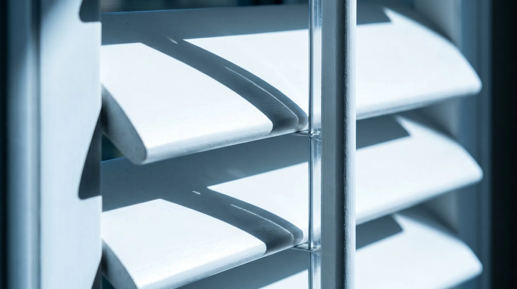Close-up of white plantation shutter louvre blades in profile showing the tilt mechanism