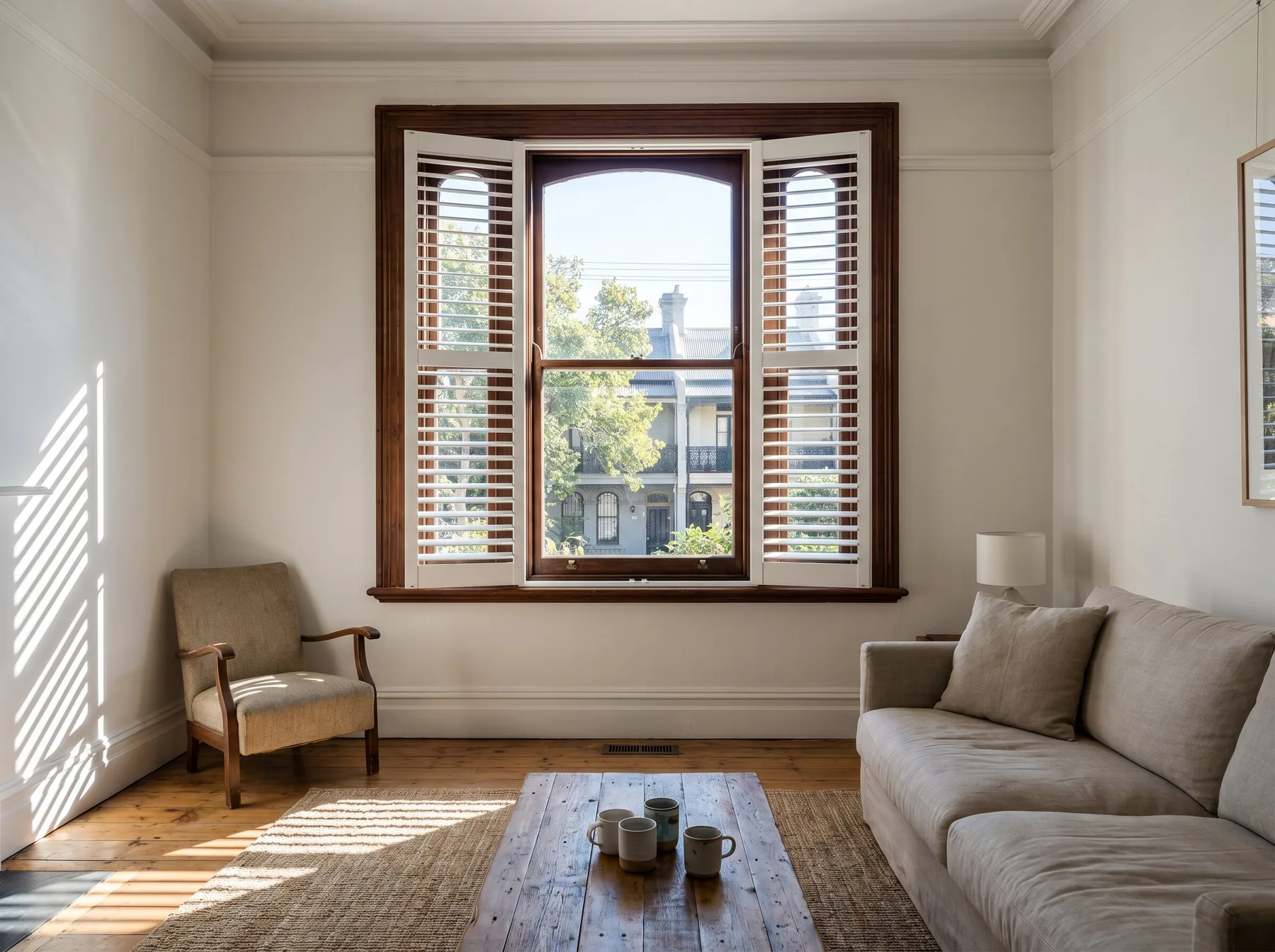 White timber plantation shutters fitted to a tall sash window in a Victorian terrace living room